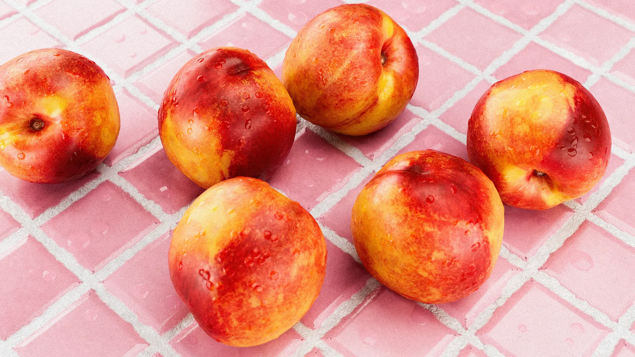 Nectarines with drips of water on them, on a pink tiled background